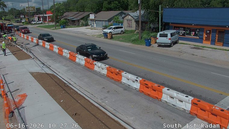 Construction workers and equipment are present on the roadway, indicating ongoing work.