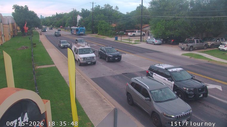 Two police cars are stopped on the roadway, one with lights on.
