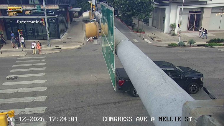 A large sign pole has fallen across the roadway, obstructing traffic.