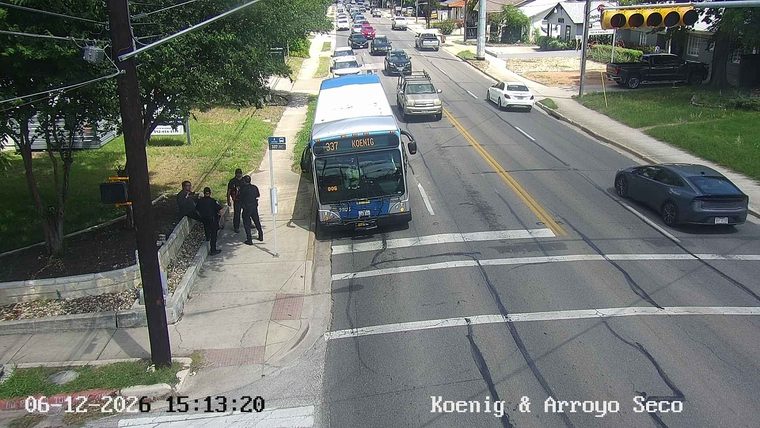 Police officers are gathered near a bus stop on the sidewalk.