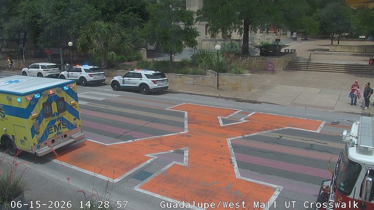 Ambulance and police vehicles are present at a crosswalk.
