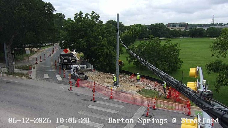Construction workers and equipment are present on the roadway.