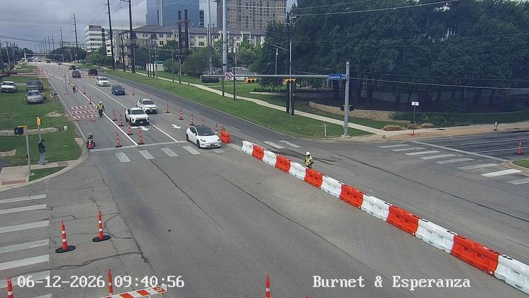 Construction workers and barriers are present on the roadway.