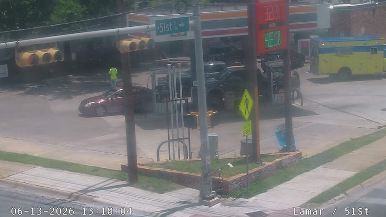 Ambulance and person in reflective vest at gas station.