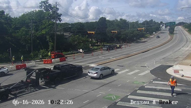 Construction workers and equipment are present on the roadway, indicating ongoing work.