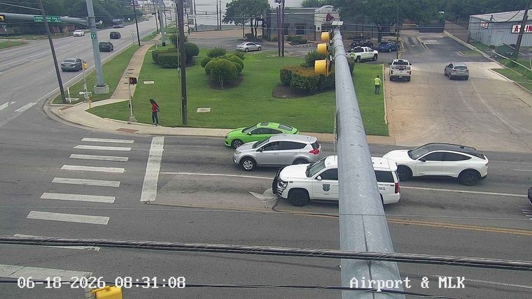Police vehicle and person in high-visibility vest at intersection.
