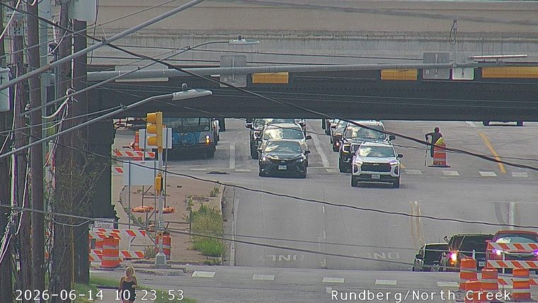Person in reflective vest directing traffic around construction cones.