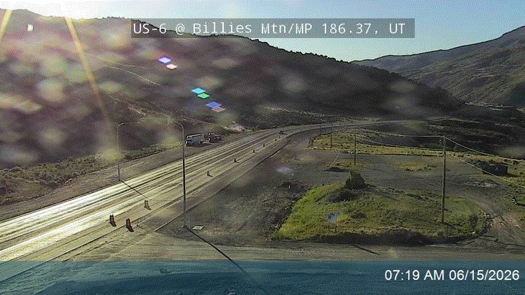 Traffic cones and vehicles suggest a roadside incident or construction ahead.