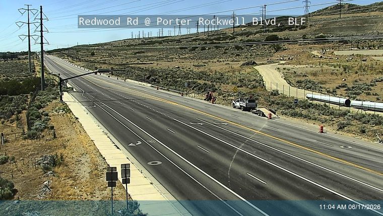 Construction vehicles and equipment are present on the shoulder of the road.