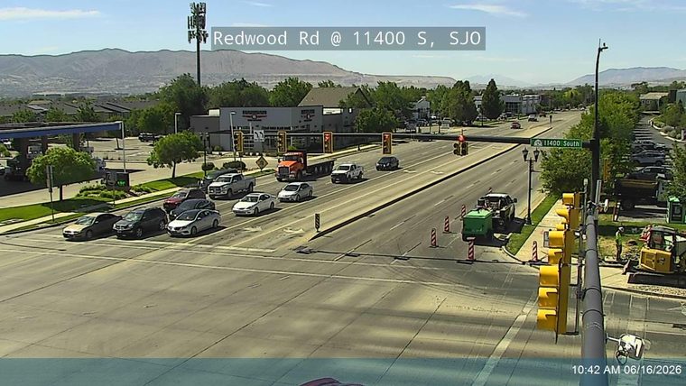 Construction workers and equipment are present on the roadside, indicating ongoing work.