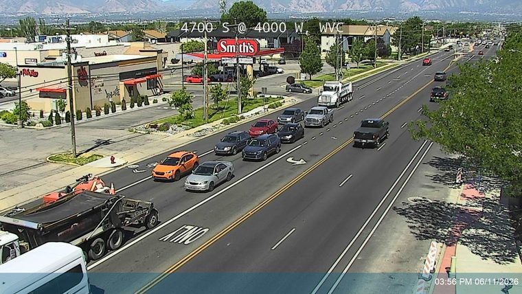 Construction vehicles and cones are present on the roadway, indicating ongoing work.