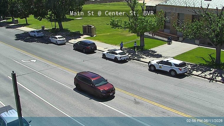 Police car parked on the side of the road with two people standing nearby.