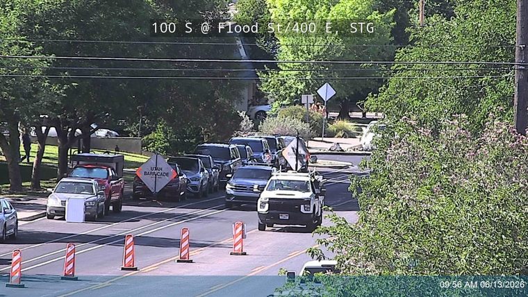 Traffic cones and barricades indicate a road closure with responders present.