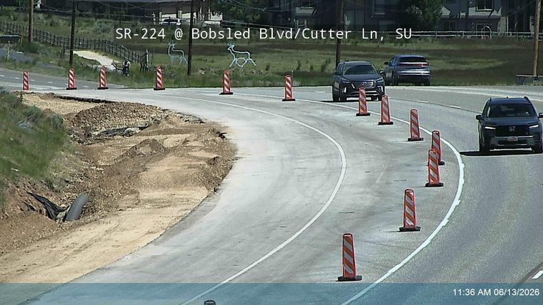Roadway partially washed out with debris and construction cones present.