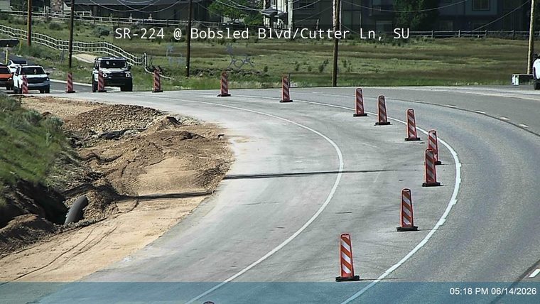 Roadway partially blocked by dirt and construction debris, with traffic cones present.