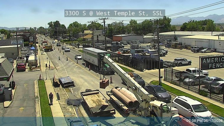 Crane and construction equipment on roadway, traffic cones present.