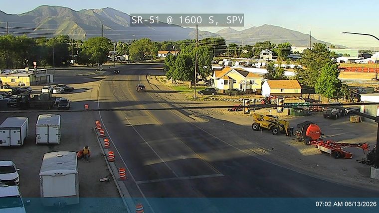 Construction workers and equipment are present on the roadside, indicating ongoing work.