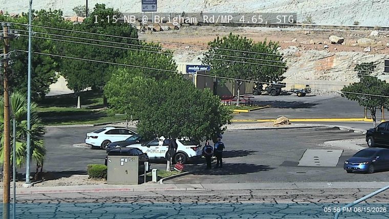 Police officers are gathered around a police car in a parking lot.