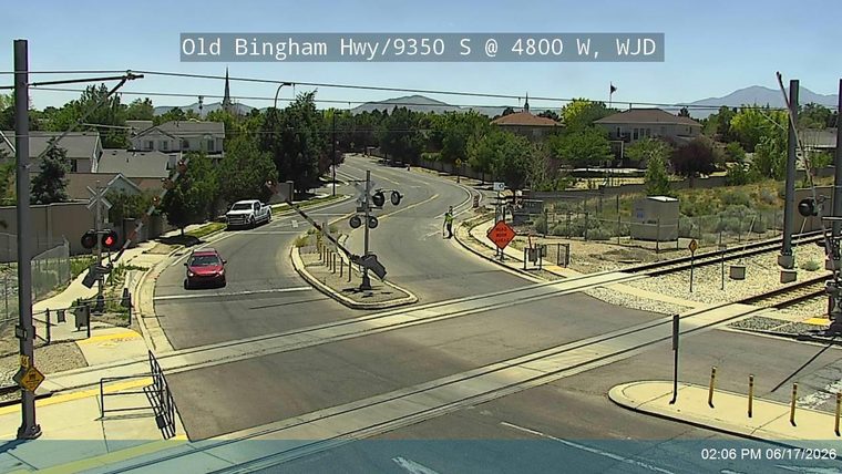 Person in reflective vest directing traffic at a railroad crossing.