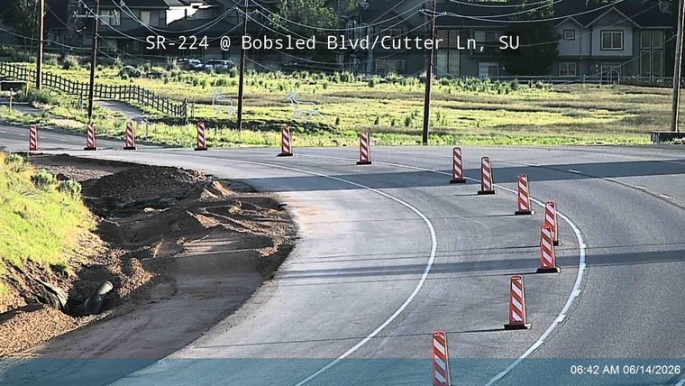 Roadway partially blocked by dirt and debris, with traffic cones present.