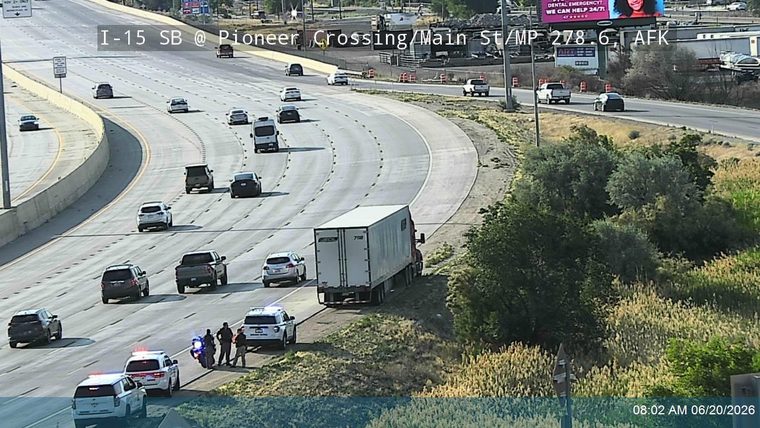 Police cars and officers on the right shoulder near a semi-truck