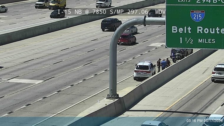 Police and civilians gathered near a parked vehicle and motorcycle on the shoulder.