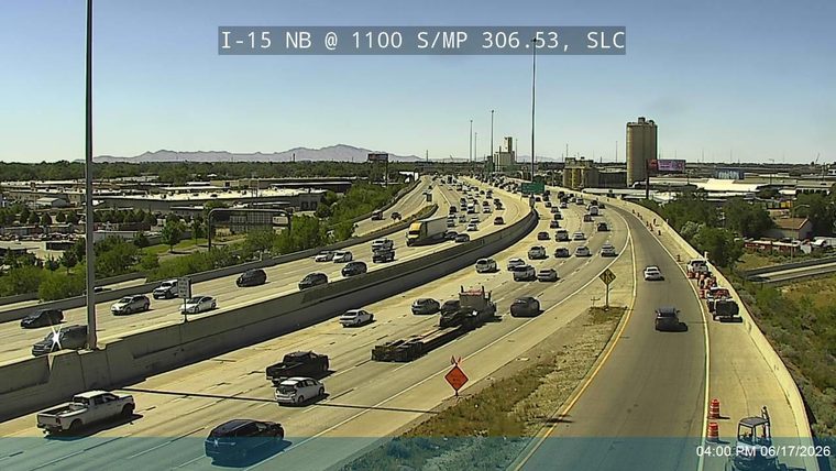 Traffic cones and a construction vehicle are present on the right shoulder of the highway.