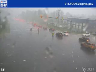 Emergency responder directing traffic at intersection during heavy rain.