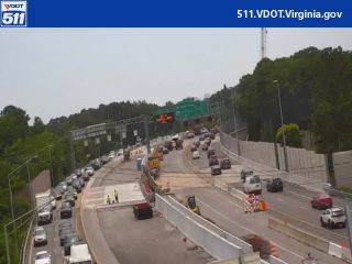 Construction workers and equipment on the roadway, causing traffic delays.