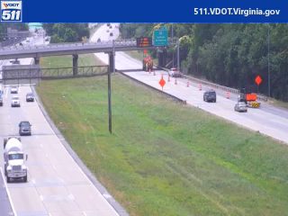Emergency responders and cones on the highway shoulder, traffic is moving.