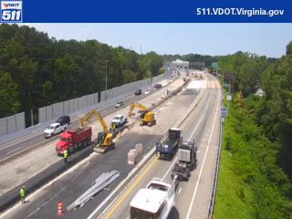 Construction vehicles and personnel are present on the roadway, indicating ongoing work.