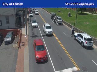 Police car and officer on the side of the road, traffic moving past.