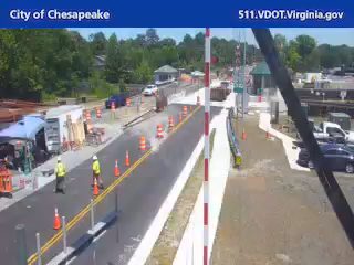 Construction workers and equipment are present on the roadway.