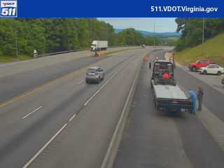 Tow truck and workers present on the right shoulder of the highway.