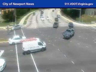 White van with ladders and emergency lights on scene at intersection.