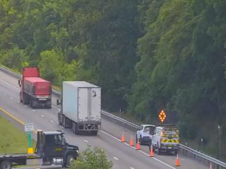 Road work with cones and emergency vehicles on the highway shoulder.