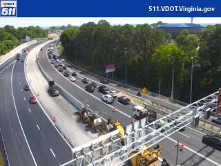 Road work with cones and equipment on the highway, traffic is slowed.
