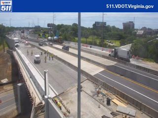 Multiple workers and vehicles present on the roadway, indicating construction or maintenance activity.