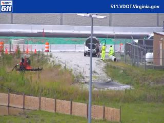 Two responders in yellow vests near a vehicle on the side of the road.