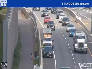 Tow truck and personnel attending to a vehicle on the side of the highway.