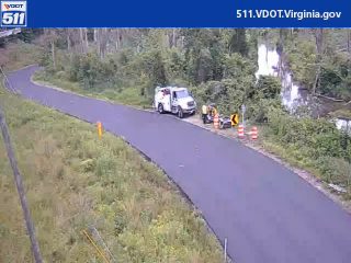 Road work with a truck, equipment, and cones on the side of the road.