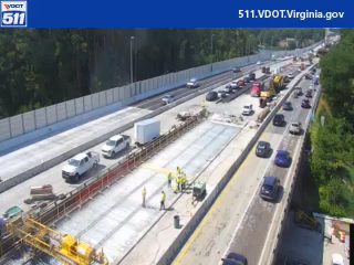 Construction workers and equipment are present on the roadway, indicating ongoing work.