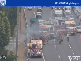 Fire truck and ambulance with emergency lights on and firefighters on the roadway