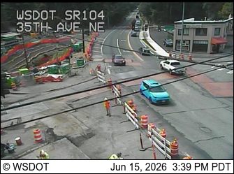 Construction workers and equipment on the roadway indicate ongoing work.