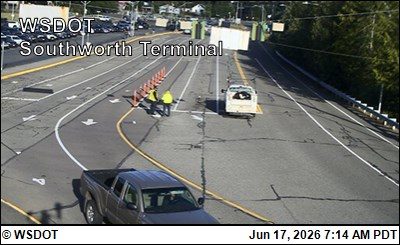 Two workers in high-visibility vests are near traffic cones and a vehicle.