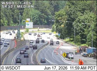 Construction crew and equipment visible on the right shoulder of the highway.