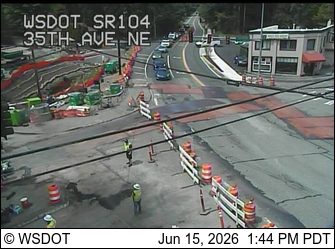Construction workers and equipment present on a roadway with traffic control measures.