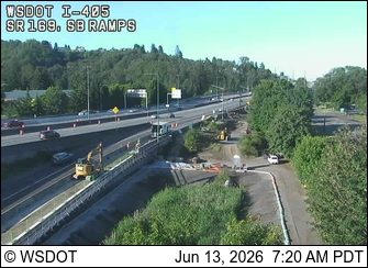 Construction vehicles and personnel on the side of the highway, possibly responding to an incident.