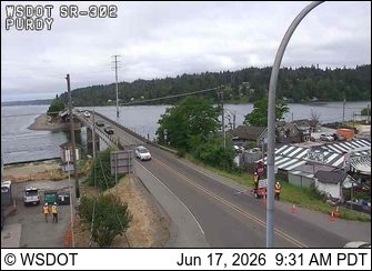 Emergency responders and vehicles on the side of the road near a bridge.