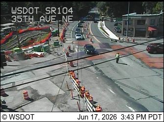 Construction zone with worker present, traffic cones, and barriers.